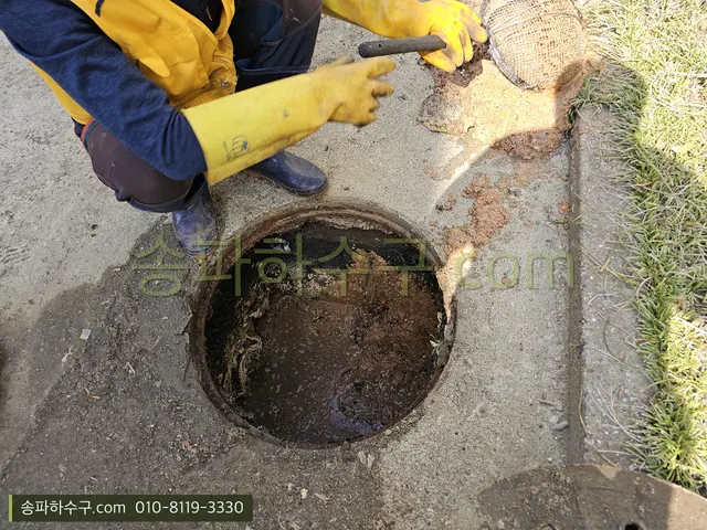 마당 오수받이를 열고 막힌 오물을 걷어내는 작업